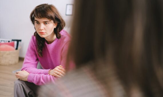 A Woman Wearing a Pink Sweater Talking to a Therapist 570x342 - Exploring the Core Therapies Used in Addiction Treatment