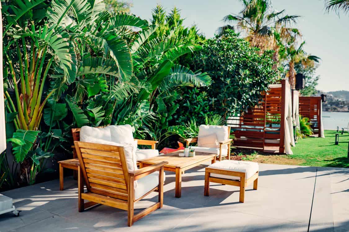 outdoor patio with wooden furniture surrounded by tropical plants - How the 2026 Water Supply Picture Is Reshaping Tropical Yards Across San Diego County
