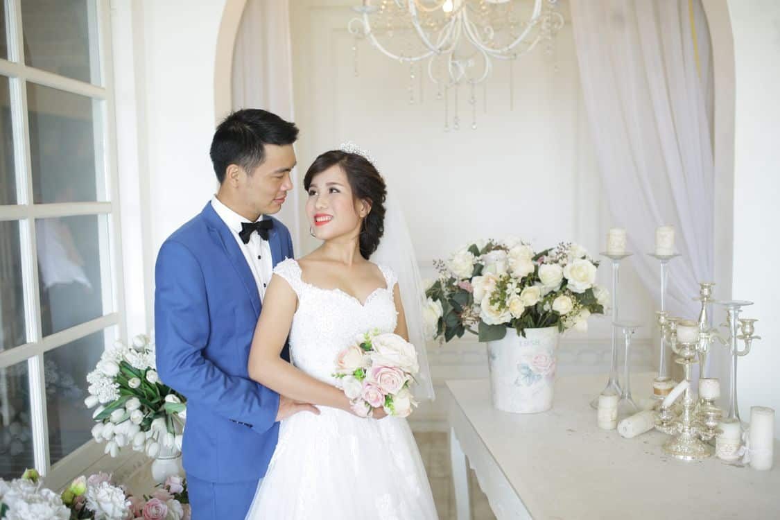 Asian bride and groom in elegant attire posing indoors - Singapore's Marriage Numbers Just Hit a Decade Low. What That Means for Small Weddings